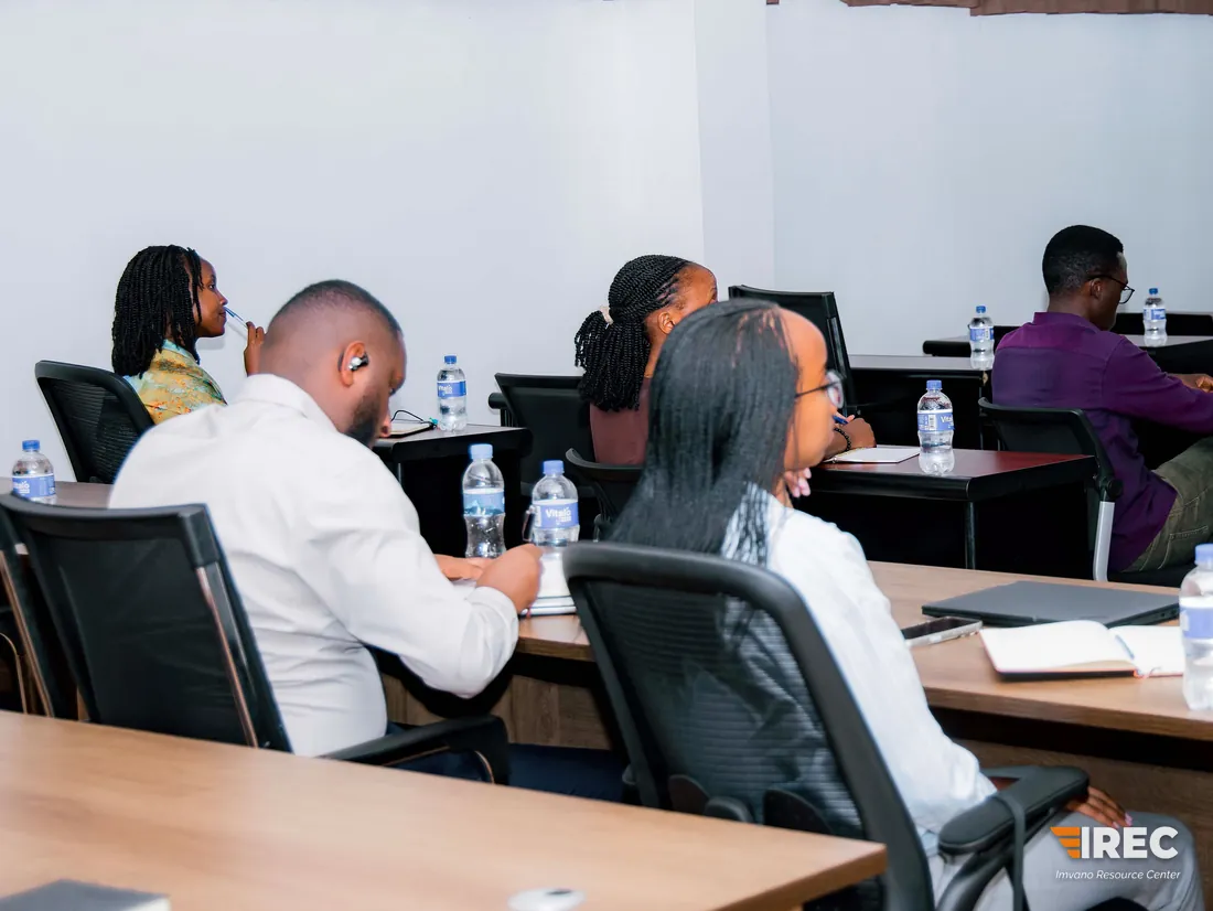 The training room seen from the back, with participants seated at desks facing the front and water bottles and notebooks on the desks.